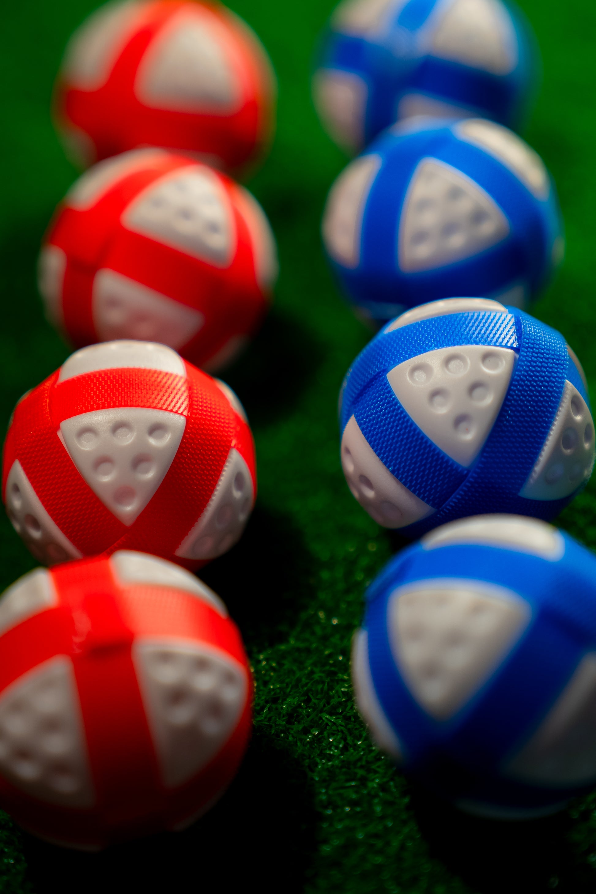Close-up of red and blue Golf Pong velcro balls with dimpled foam panels resting on green turf